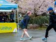 Two women stretch underneath blossoming cherry trees ahead of the Gresham Lilac Run at Main City Park.