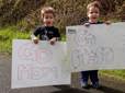 Two young boys stand on the Springwater Trail holding signs to support their mothers at the Gresham Lilac Run.