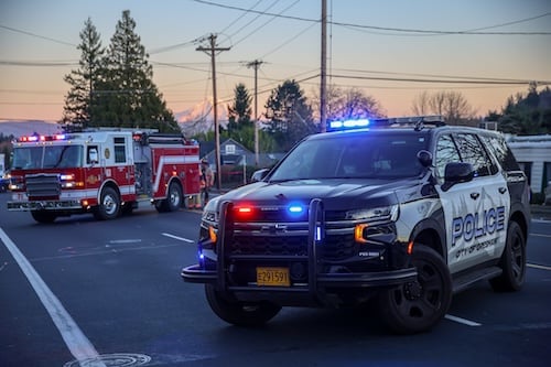 A fire truck and a police cruiser are parked and Mt. Hood during sunset can be seen in the background.