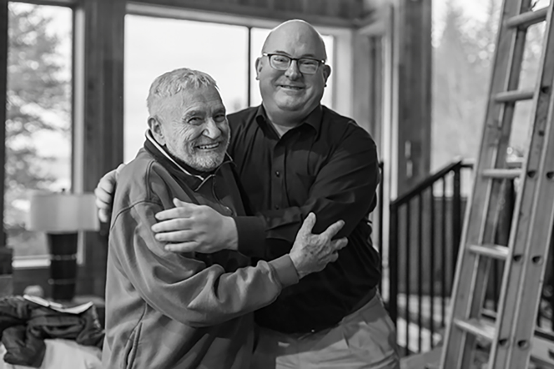 Frank Motley and Eric Schmidt stand close smiling. 