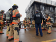 Fire academy recruits listen to their instructor as they prepare to enter a smoking structure at the Portland Fire Training Center.