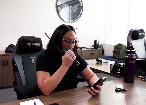Customer Safety Specialize sits at desk, speaking into a handheld radio to talk with Police.
