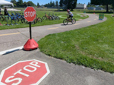 Stop signs at the entrance of Davis Park with a child riding a bike in the distance. 